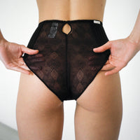 Close up of a woman's bottom. She is wearing the Bea high wasit pantie in color Licorice and adjusting it with her hands