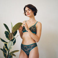 Model standing next to plant wearing Semiromantic Lingerie set made from Green lace.
