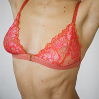 Close up of a Semiromantic triangle bra worn by a model. The bra is made of recycled lace in Tangerine color.